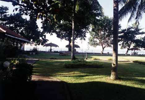 Standing in the shadow of our Sasak-style cottage looking toward the beach, which is the other side of the shaded tables. - jpg - 19173 Bytes