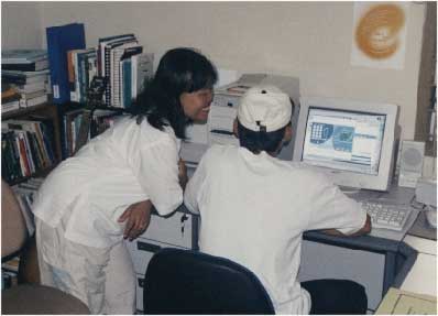 Ibu Tari and Pak Kris use the internet phone to talk to Hannah and Eloise Neufeld in Canada. Hannah and her husband David were our predecessors in the house. - jpg - 13901 Bytes